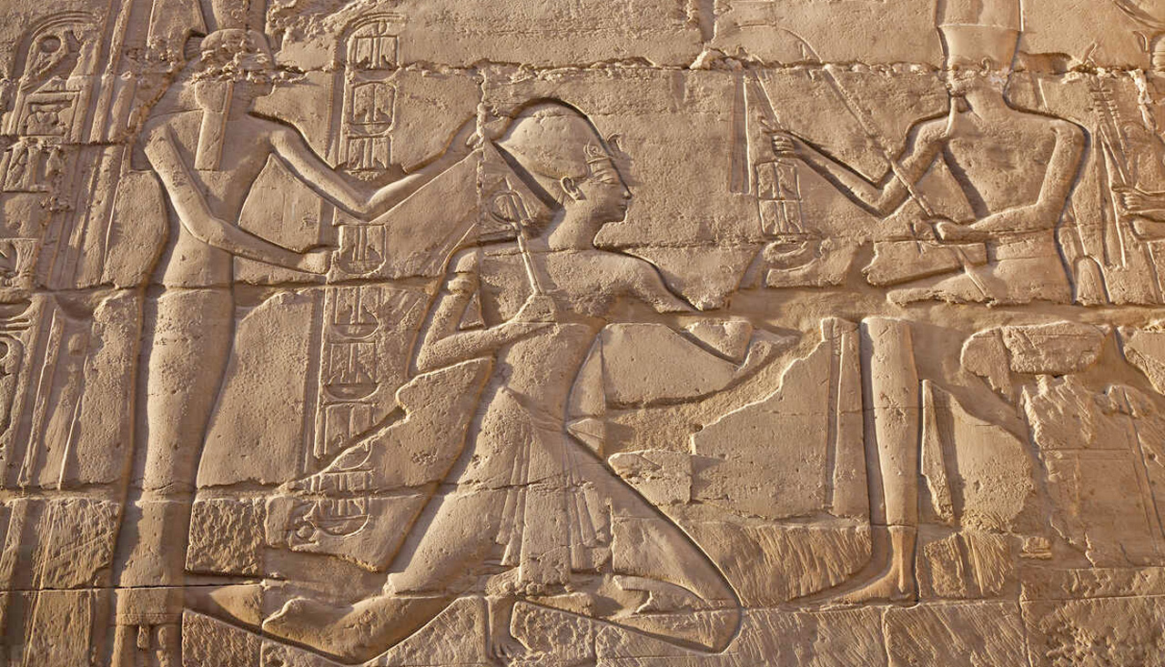 Close up of stone wall with ancient Egyptian bas-relief depicting Pharaoh.
